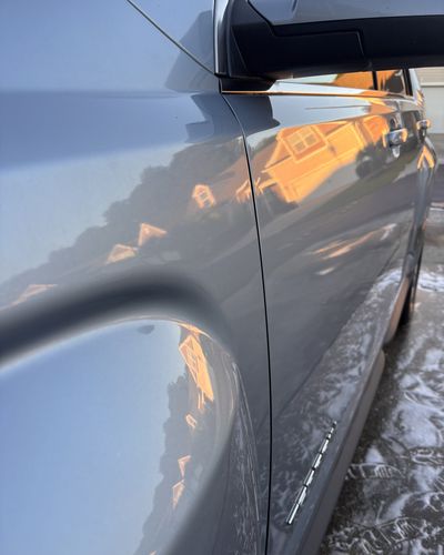 Glossy silver-blue GMC paint reflecting the sunset